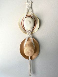 two hats hanging on the wall with a tasseled hat holder attached to it