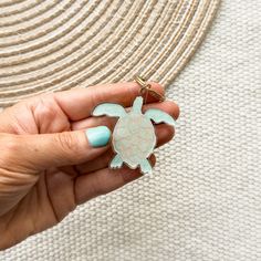 a person holding a turtle keychain in their left hand and wearing a hat