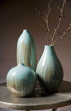 two blue vases sitting on top of a table next to each other with flowers in them