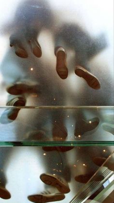 the reflection of two people's shoes in a glass shelf