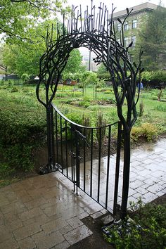 an iron gate in the middle of a garden