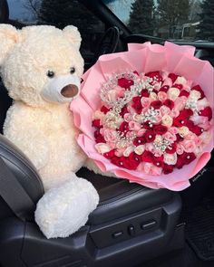 a teddy bear sitting in the back seat of a car holding a bouquet of roses