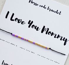 a bracelet that says i love you mommy on the front and back of it with a beaded cord