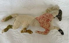 a stuffed animal laying on top of a white bed covered in lace and fabric material