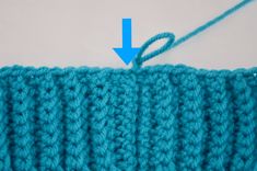 the crochet stitch has an arrow pointing up at it's center and is blue