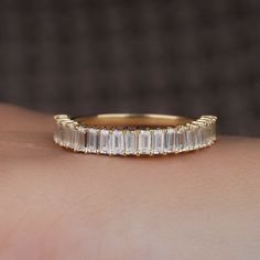 a woman's hand wearing a gold band with baguettes on it