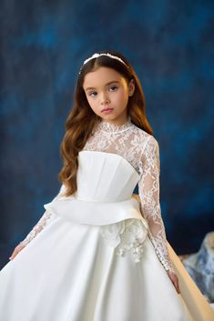 Transform your little princess into a fairy-tale vision with the Pentelei 3713 Girls Communion Gown and Flower Girl Dress. Featuring a sheer lace neckline with long sleeves, a corset bodice with bone for the perfect fit, and a peplum skirt for added flair. The full floor length skirt with a hint of train adds a touch of elegance, while the lace back and crystal buttons provide a touch of sparkle. Complete with a corset tie in the back with a beautiful bow accent, this gown is sure to make your l Chantilly Lace Styles, First Communion Dress, Kids Gown, Girls Pageant Dresses, Communion Dresses, Illusion Neckline, Lace Neckline, Pageant Dress, Chantilly Lace