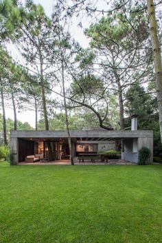 a house in the middle of some trees and grass with a picnic table next to it