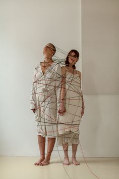 two women standing next to each other in front of a wall with lines on it