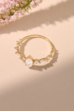 a gold ring sitting on top of a table next to pink flowers