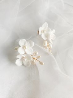 two white flowers and pearls on a white cloth