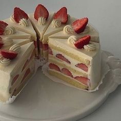 a cake with white frosting and strawberries is cut in half on a plate