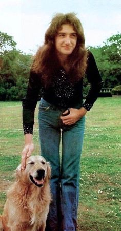 a woman standing next to a dog in a field