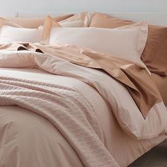 an unmade bed with pink sheets and pillows