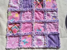 a pink and purple patchwork blanket laying on top of a bed