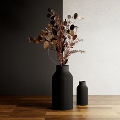 two black vases sitting on top of a wooden table next to each other with dried plants in them