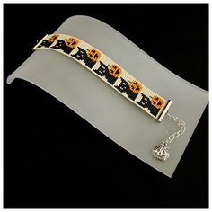 a beaded bracelet with an orange and black flower design on the front, sitting on top of a piece of plastic