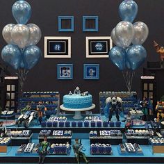 a birthday party with blue and silver decorations, balloons and pictures on the wall behind it