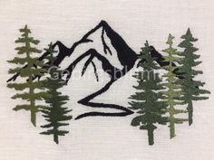 a mountain scene with trees and a river in the middle is embroidered onto a white shirt