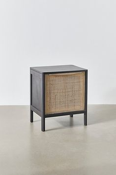 a black and brown cabinet sitting on top of a cement floor next to a white wall