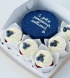 cupcakes with white frosting and blueberries in a box