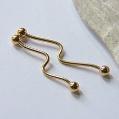 two gold balls are attached to the end of a pair of nose piercings on a white surface