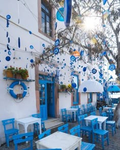 an outdoor cafe with blue chairs and tables on the side of the street in front of a white building