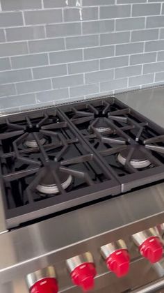 a stainless steel gas stove with red knobs