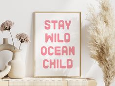 a pink poster that says stay wild ocean child next to some vases and flowers