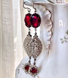 Elegantly long, red and rhinestone earrings, these lovelies are created from remnant rhinestone jewelry parts, red and rhinestone glass buttons, and deep red Swarovski crystals.  They are quite long at 3 1/4" not including the ear wire. I work with antique and vintage parts. Some may show signs of wear or age. Please look at each picture closely. I have tried to show all aspects of my work. Please contact me before purchasing if you have any questions or would like more clarity in a picture. I like to think that older items have a character that newer parts have not yet earned. Assemblage Earrings, Formal Jewelry, Antique Buttons, Earrings Red, Long Red, Glass Buttons, Long Pendant, Rhinestone Jewelry, Rhinestone Earrings