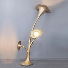 a lamp that is sitting on the floor in front of a wall with two lights