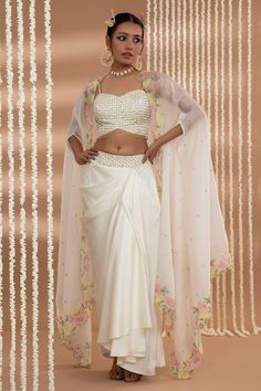 Ivory cape with floral embroidered border. Paired with a blouse with sequin work and draped skirt. - Aza Fashions Lehenga Cape Style, Wedding Sets With Draped And Cape Sleeves, Fitted Sets With Pearl Embroidery And Traditional Drape, Festive Lehenga With Pearl Embroidery And Cape Sleeves, Georgette Dresses With Pearl Embroidery And Cape Sleeves, Designer Lehenga With Pearl Embroidery And Cape Sleeves, Traditional Sets With Pearl Embroidery And Cape Sleeves, Designer Sets With Pearl Embroidery And Cape Sleeves, Off White Traditional Drape Party Sets