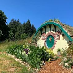 a hobbot house in the middle of a field with lots of plants and flowers around it