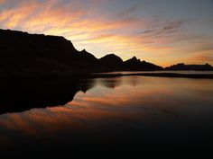 the sun is setting over some mountains and water