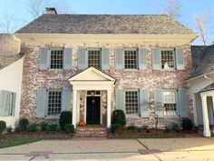 a large brick house with white shutters on the front and side windows, along with an entry door