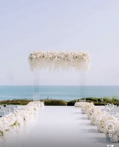 an outdoor ceremony setup with white flowers and greenery on the aisle, overlooking the ocean