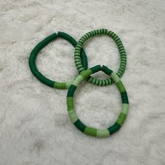 three green bracelets sitting on top of a white rug