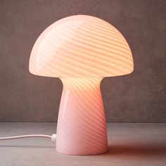 a mushroom shaped lamp with a cord plugged in to it's base and the light turned on