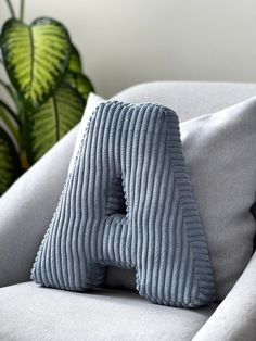 a blue pillow sitting on top of a white couch next to a potted plant