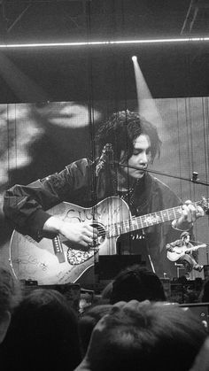 a man playing guitar in front of a crowd