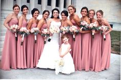 a group of women standing next to each other in front of a building with bouquets