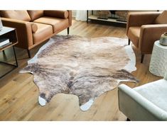 a living room with two chairs and a cow hide rug