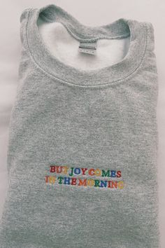 Our 'But Joy Comes In The Morning' embroidered heavy-blend sweatshirt is made with air-jet spun yarn for a soft and comfy fit. Unisex fit. #christiansweatshirt #christianembroideredsweatshirt #embroideredchristiansweatshirt #cuteembroideredsweatshirt #aestheticembroideredsweatshirt #embroideredsweatshirt #cutesweatshirtforwomen #faithsweatshirt #positivtysweatshirt #biblesweatshirt #bibleversesweatshirt #christianclothing #christianapparel #jesussweatshirt #christiangiftforwomen #faithshirt Cotton Crew Sweatshirt With Machine Embroidery, Crew Cotton Sweatshirt With Machine Embroidery, Long Sleeve Tops With Multicolor Embroidery And Letter Print, Multicolor Embroidered Long Sleeve Top With Letter Print, Multicolor Embroidery Long Sleeve Top With Letter Print, Crew Neck Sweatshirt With Multicolor Embroidery, Multicolor Embroidered Text Crew Neck Sweatshirt, Crew Neck Cotton Sweatshirt With Machine Embroidery, Cotton Crew Neck Sweatshirt With Machine Embroidery