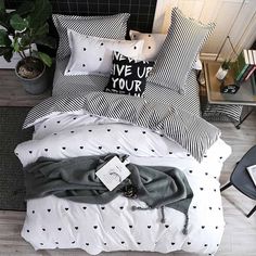 a bedroom with black and white bedding, pillows and a plant in the corner