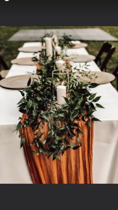 the table is set with candles and greenery