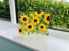 a glass block with sunflowers painted on it in front of a window sill