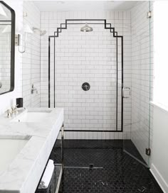 a white tiled bathroom with black and white tile flooring, two sinks and a walk in shower