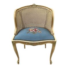 an antique chair with blue upholstered seat and gold trimming on the back