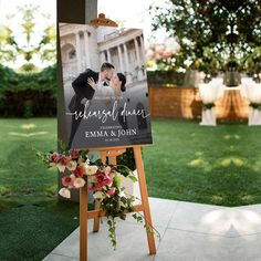 an outdoor wedding sign with flowers and greenery