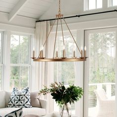 a living room filled with furniture and a chandelier hanging over it's windows